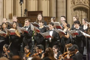 A large choral ensemble performs in formal dress with orchestra at a Manhattan School of Music concert in Riverside Church