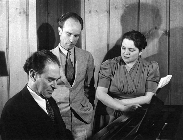 man at piano, man and woman watching