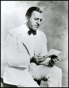 man in white suit reading a letter