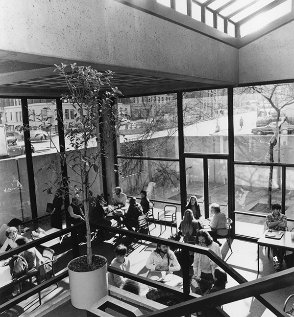 1970s modern room with dining tables, filled with students