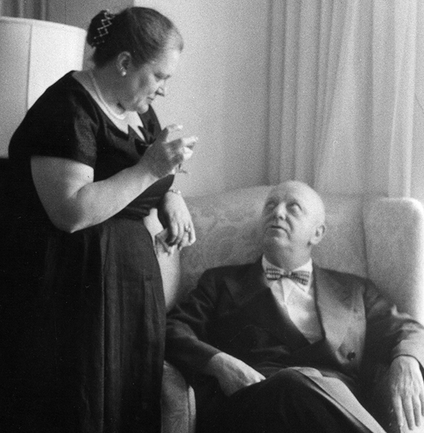 woman holding a drink talking to a man seated in chair