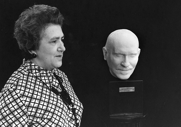 woman standing next to plaster bust of man's head